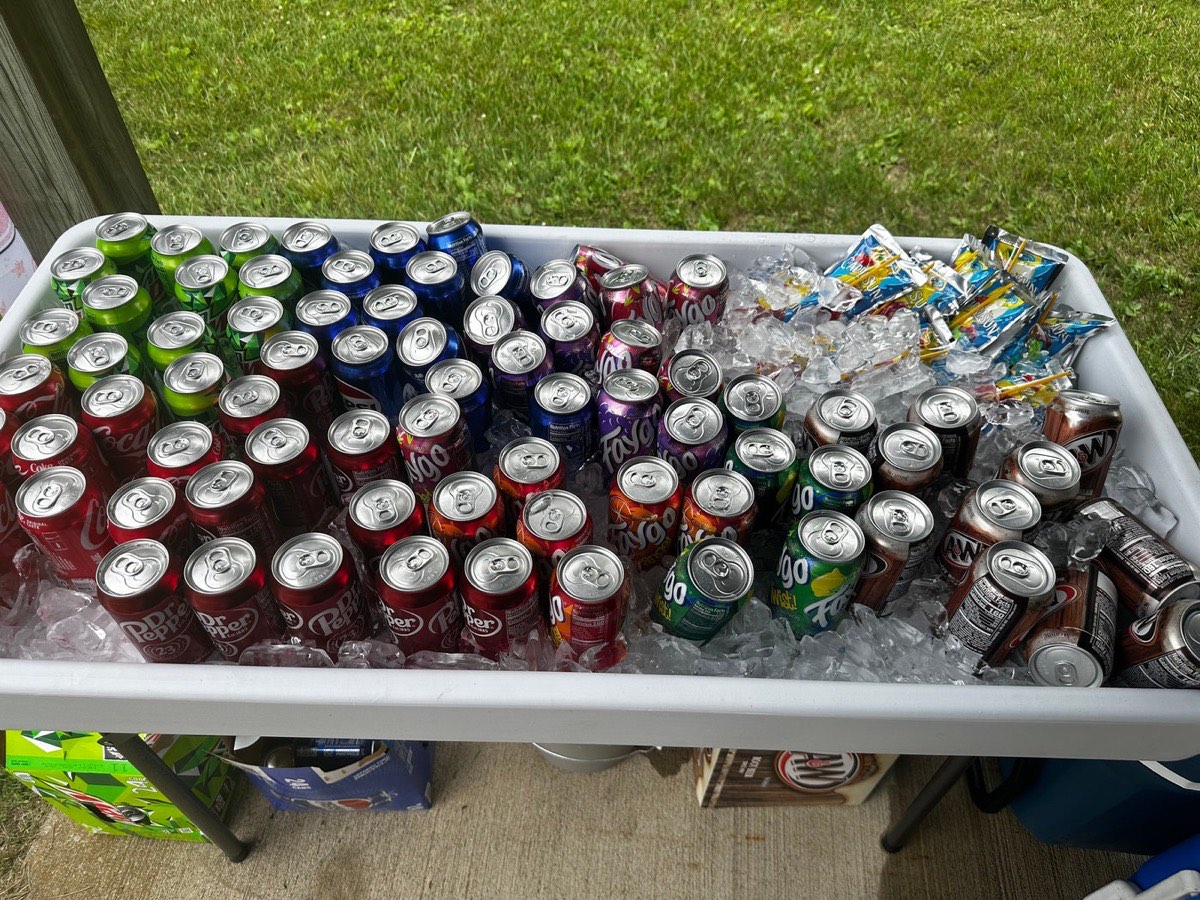 A 4-foot beverage table filled with ice and chilled cans of pop and beer, ready for a backyard event