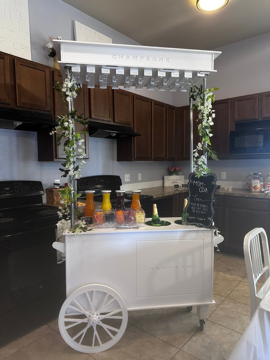 The Lace & Beads all-white Champagne Cart set up as a Mimosa Bar with fresh juices and garnishes